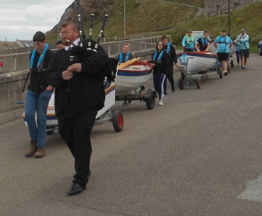 Image of procession of boats led by a Piper.