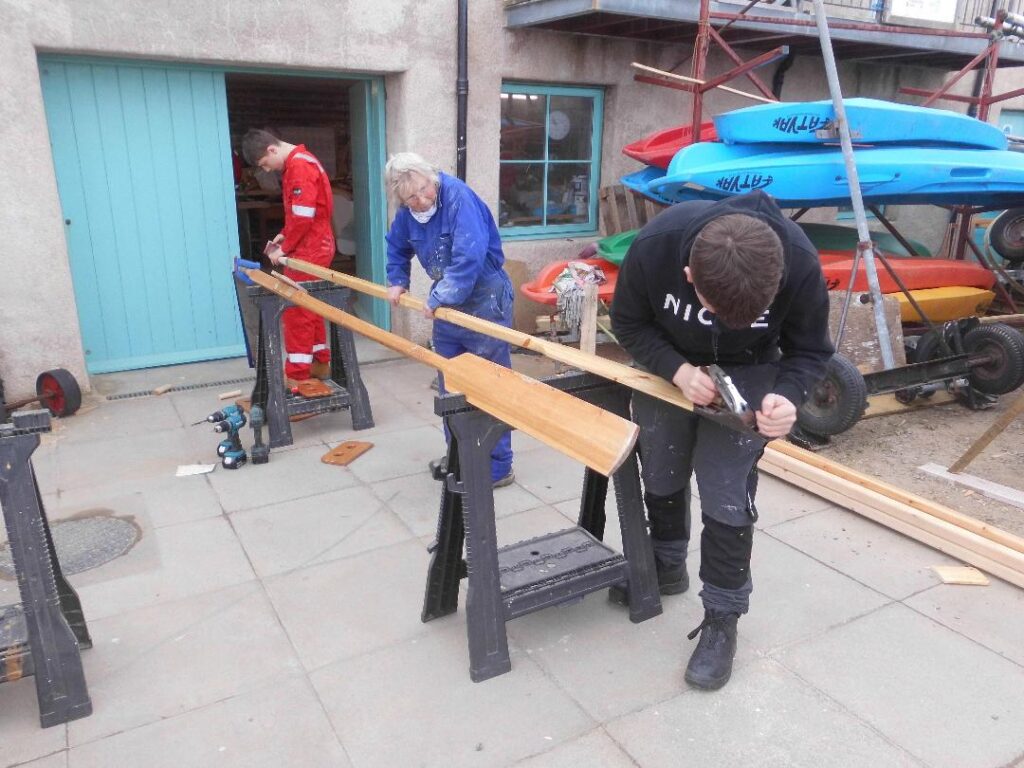 Image of two Banff Academy Students and a sea school boat builder making oars outside the sea school workshop